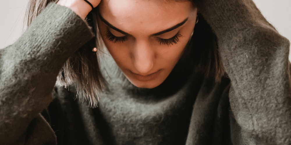 Frau halt sich den Kopf mit den Händen – Symbolbild für den Online-Selbsttest bei Angst