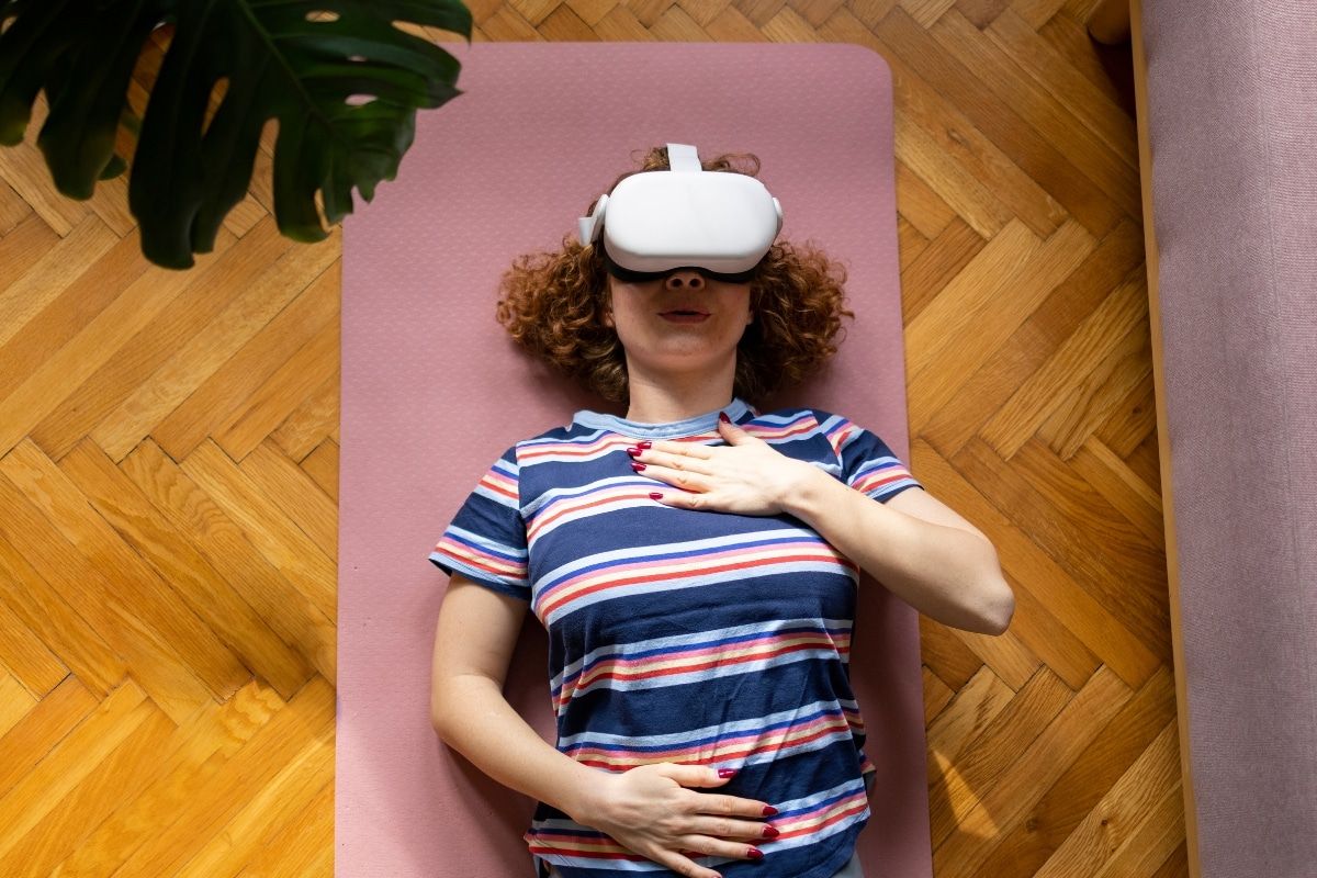 Junge Frau liegt auf dem Boden und nutzt Novego RELAX Virtual Reality App mit VR-Brille